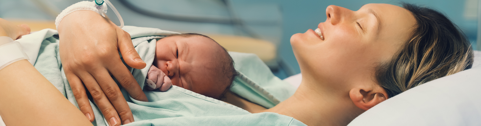 a baby and new mother lying in a hospital bed