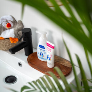 a bathroom sink with a toy animal and a bottle of lotion