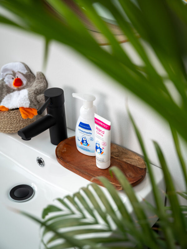 a bathroom sink with a toy animal and a bottle of lotion